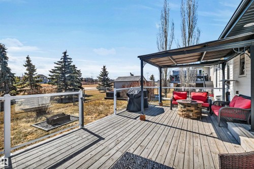 Spacious wooden deck featuring a covered area, and a glass railing overlooking the yard - 5201 40 Avenue, Beaumont, AB - Outdoor With Deck Patio Veranda