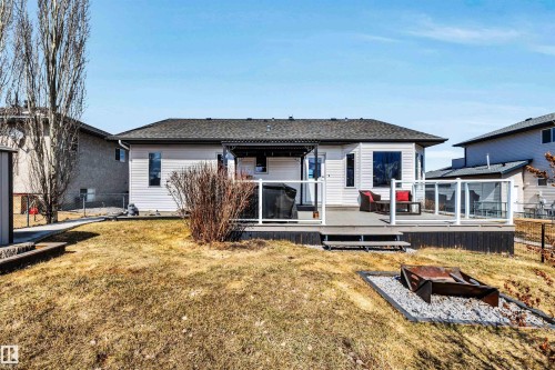 The property features a spacious deck with clear panel railings and steps leading to a yard with a fire pit area - 5201 40 Avenue, Beaumont, AB - Outdoor With Deck Patio Veranda