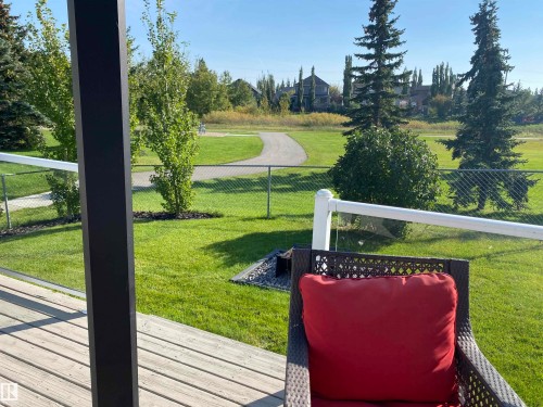 The property features an outdoor deck with wood planks, a black support beam, and a white railing with transparent panels - 5201 40 Avenue, Beaumont, AB - Outdoor With View
