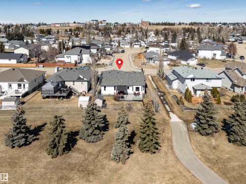 The property features a white exterior with a dark gray roof, an elevated porch, and a storage shed in the backyard - 5201 40 Avenue, Beaumont, AB - Outdoor With View