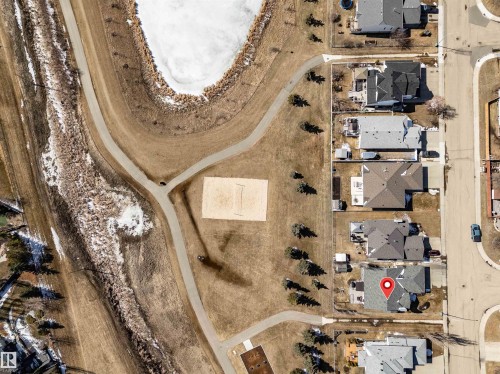 Aerial view showcasing the property's proximity to a paved pathway system, a public park with a sand court, and a body of water - 5201 40 Avenue, Beaumont, AB - Indoor