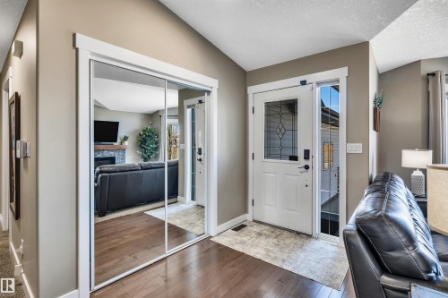 Entryway featuring hardwood flooring, a white front door with decorative glass, and a mirrored closet - 5201 40 Avenue, Beaumont, AB - Indoor Photo Showing Other Room