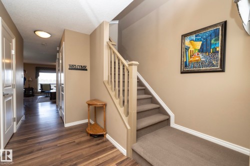Entryway featuring wood-look flooring and a carpeted staircase with a wooden banister - 130 Kirpatrick Way, Leduc, AB - Indoor Photo Showing Other Room