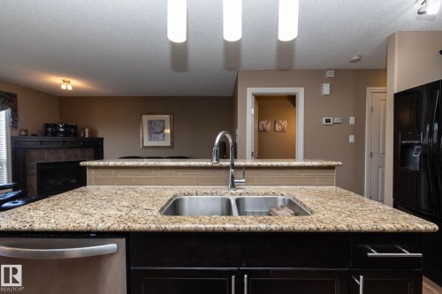 The kitchen features a double basin stainless steel sink with a chrome faucet, set within a granite countertop - 130 Kirpatrick Way, Leduc, AB - Indoor Photo Showing Kitchen With Double Sink