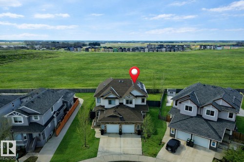 The property features a two-story design with an attached two-car garage, a paved driveway, and a well-maintained lawn - 130 Kirpatrick Way, Leduc, AB - Outdoor With View