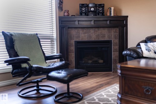 The living area features a fireplace with a dark wood mantel and a tiled surround - 130 Kirpatrick Way, Leduc, AB - Indoor Photo Showing Living Room With Fireplace