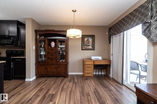 The property features a bright dining area with wood-look flooring, a chandelier, and a sliding glass door leading to an outdoor space - 130 Kirpatrick Way, Leduc, AB - Indoor