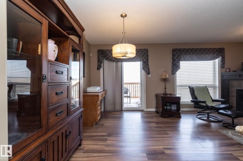 Living area with wood-style flooring, a window offering natural light, and a sliding glass door leading to an outdoor space - 130 Kirpatrick Way, Leduc, AB - Indoor With Fireplace