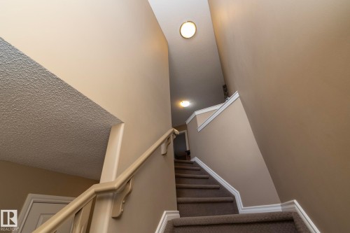 Staircase featuring neutral-toned walls, a carpeted tread, and white trim details - 130 Kirpatrick Way, Leduc, AB - Indoor Photo Showing Other Room