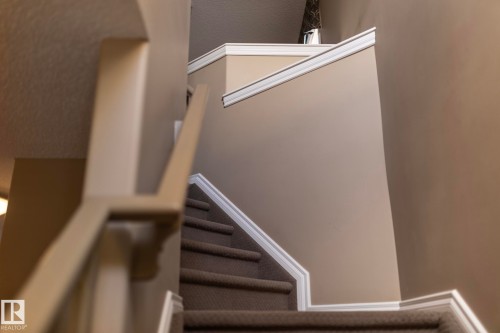 The property features a staircase with carpeted treads and white trim - 130 Kirpatrick Way, Leduc, AB - Indoor Photo Showing Other Room