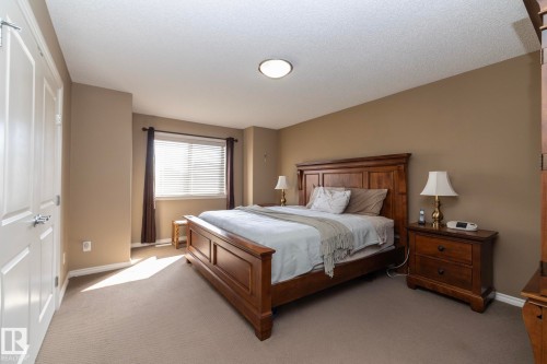 This bedroom features a window with blinds and dark curtains, carpeted flooring, and a ceiling light fixture - 130 Kirpatrick Way, Leduc, AB - Indoor Photo Showing Bedroom