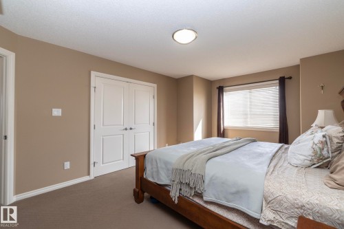 This room features neutral-toned walls, a window with blinds, and white bi-fold doors - 130 Kirpatrick Way, Leduc, AB - Indoor Photo Showing Bedroom