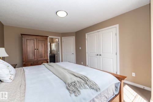 Bedroom with warm-toned walls, featuring a ceiling light fixture and white bi-fold closet doors - 130 Kirpatrick Way, Leduc, AB - Indoor Photo Showing Bedroom