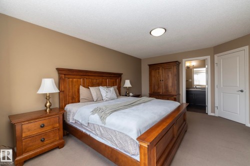 This inviting bedroom features neutral-toned walls, a textured ceiling, and carpeting - 130 Kirpatrick Way, Leduc, AB - Indoor Photo Showing Bedroom