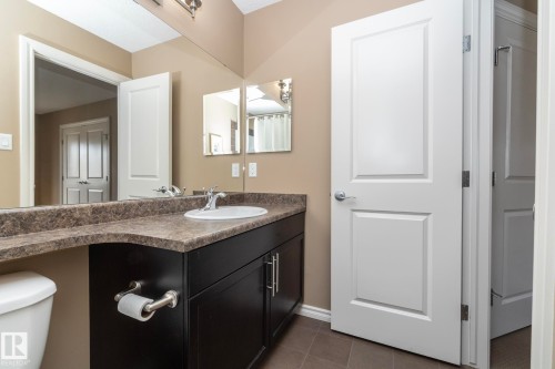 The bathroom features a vanity with a dark wood cabinet, a light-colored countertop, and a white sink with a chrome faucet - 130 Kirpatrick Way, Leduc, AB - Indoor Photo Showing Bathroom