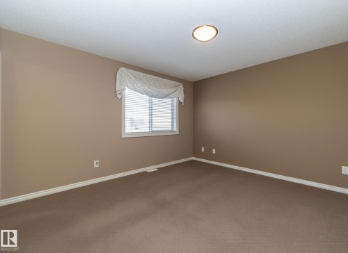 This inviting room features neutral-toned walls, plush carpet, and a window fitted with blinds, providing natural light - 130 Kirpatrick Way, Leduc, AB - Indoor Photo Showing Other Room