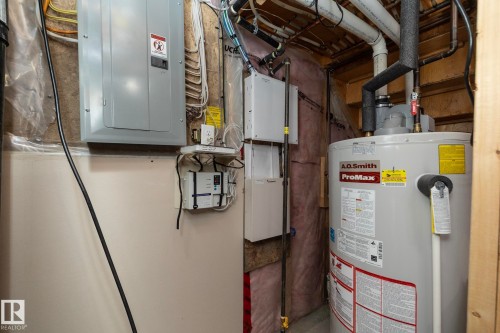 The property features a hot water heater and an electrical panel, showcasing essential utilities - 130 Kirpatrick Way, Leduc, AB - Indoor Photo Showing Basement