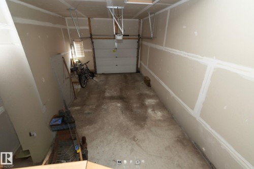 The property features a garage with an overhead door, concrete flooring, and light-colored walls - 130 Kirpatrick Way, Leduc, AB - Indoor Photo Showing Garage