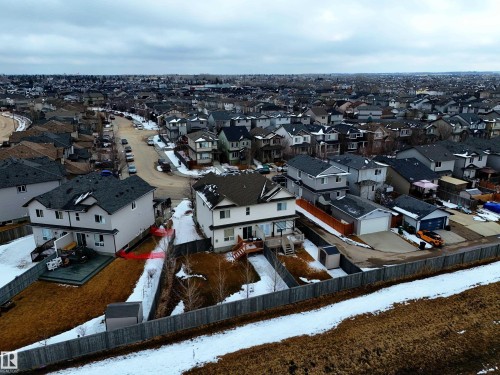 This aerial view showcases the property within a residential setting, featuring a fenced yard with some snow cover and a visible shed - 130 Kirpatrick Way, Leduc, AB - Outdoor
