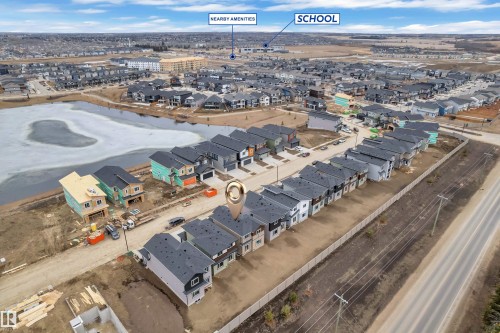 Aerial view of the property and its surrounding area, featuring a street with houses and a nearby body of water - 237 Linden Loop, Leduc, AB - Outdoor With View