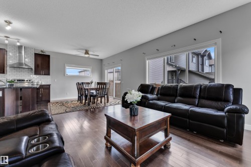 Open concept living area featuring hardwood flooring, a large window, and a sliding glass door providing access to the outdoors - 1452 30 Street, Edmonton, AB - Indoor Photo Showing Living Room