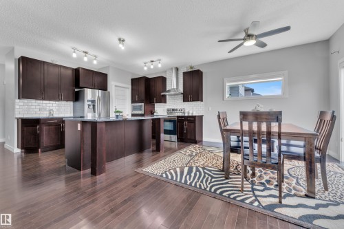 The kitchen features dark wood cabinetry, stainless steel appliances, and a central island with a countertop - 1452 30 Street, Edmonton, AB - Indoor Photo Showing Other Room