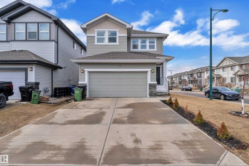 The property features a two-story exterior with light gray siding and stone accents, a gray garage door, and a concrete driveway - 1452 30 Street, Edmonton, AB - Outdoor With Facade