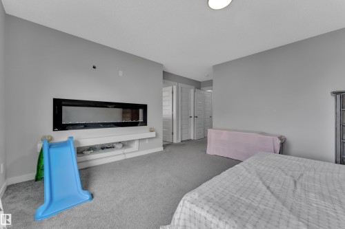 This room features a modern linear fireplace with a white floating shelf below it, light gray walls, and gray carpeted flooring - 1452 30 Street, Edmonton, AB - Indoor Photo Showing Bedroom