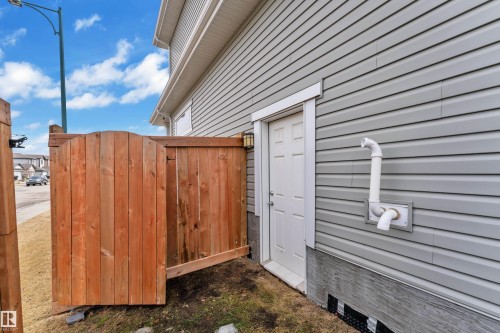 The property features grey horizontal siding, a white exterior door, and a brown wooden fence - 1452 30 Street, Edmonton, AB - Outdoor With Exterior