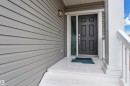 The property features an inviting entrance with light gray siding, a dark paneled front door, and a white porch with railings - 1452 30 Street, Edmonton, AB  - Outdoor With Exterior 