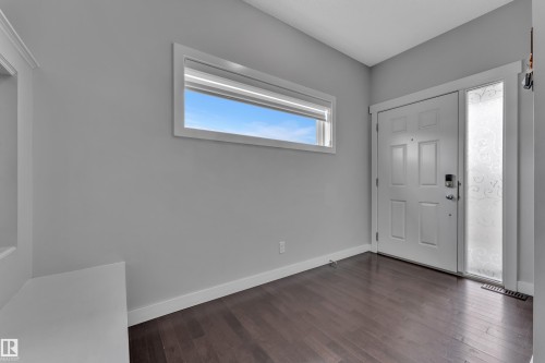 Entryway with dark wood flooring, a white paneled door, and a frosted glass sidelight with a decorative pattern - 1452 30 Street, Edmonton, AB - Indoor Photo Showing Other Room