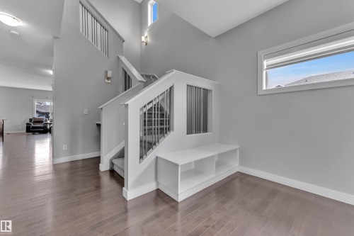 This property features hardwood flooring, a staircase with carpeted treads and white banisters, and a built-in bench with storage - 1452 30 Street, Edmonton, AB - Indoor Photo Showing Other Room