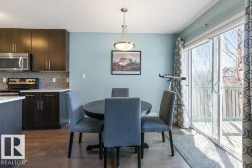 The dining area features wood flooring, a ceiling-mounted light fixture, and a sliding glass door providing access to an exterior deck - 3119 Carpenter Landing Landing, Edmonton, AB - Indoor