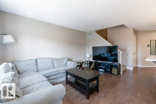 The living area features warm wood flooring and neutral wall tones - 3119 Carpenter Landing Landing, Edmonton, AB - Indoor Photo Showing Living Room