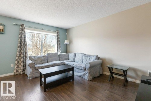 The living area features hardwood floors and a large window, providing natural light - 3119 Carpenter Landing Landing, Edmonton, AB - Indoor Photo Showing Living Room