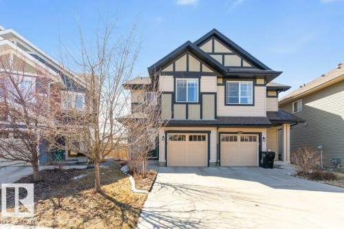 The property features a two-car garage, a paved driveway, and a front yard with trees - 3119 Carpenter Landing Landing, Edmonton, AB - Outdoor With Facade