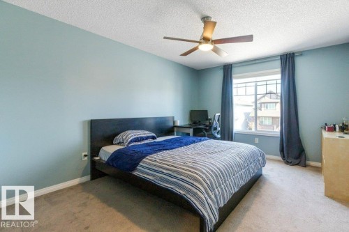 This room features light blue walls, a window with dark curtains, and a ceiling fan with an integrated light fixture - 3119 Carpenter Landing Landing, Edmonton, AB - Indoor Photo Showing Bedroom