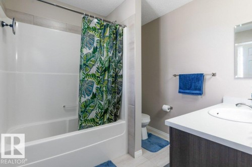 Bathroom featuring a white bathtub and shower combination with a dark shower head, a toilet, and a vanity with a white countertop and an integrated sink - 3119 Carpenter Landing Landing, Edmonton, AB - Indoor Photo Showing Bathroom