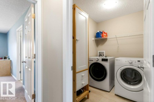 Dedicated laundry area featuring a front-loading washing machine, a clothes dryer, and a wall-mounted wire shelf - 3119 Carpenter Landing Landing, Edmonton, AB - Indoor Photo Showing Laundry Room