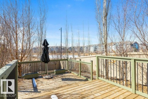 The property features a wooden deck with a green and black railing, overlooking a body of water - 3119 Carpenter Landing Landing, Edmonton, AB - Outdoor With Deck Patio Veranda