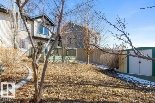 The property features a deck with lattice detailing, a shed with double doors, and a sloped yard with a stone-edged pathway - 3119 Carpenter Landing Landing, Edmonton, AB - Outdoor