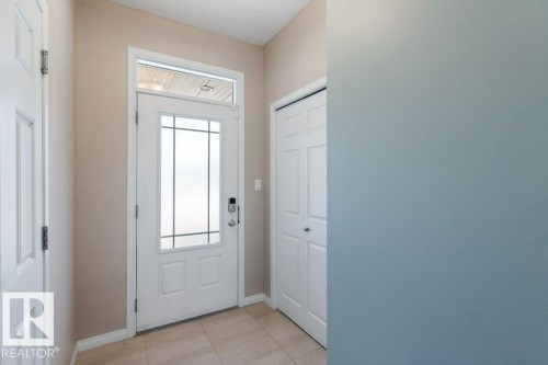Entryway featuring a white door with decorative glass inserts and a transom window, complemented by tiled flooring - 3119 Carpenter Landing Landing, Edmonton, AB - Indoor Photo Showing Other Room