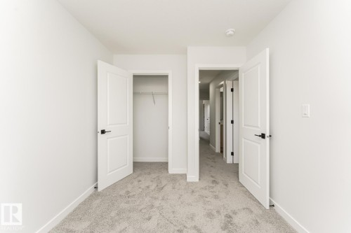 The room features light gray carpet flooring and white walls, with white doors and black hardware - 6371 King Wynd, Edmonton, AB - Indoor Photo Showing Other Room
