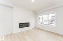Bright and open room featuring light-toned flooring, an electric fireplace, and a large window providing natural illumination - 6371 King Wynd, Edmonton, AB  - Indoor Photo Showing Living Room With Fireplace 