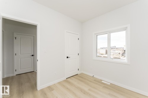 This room features light-colored plank flooring, white walls, and a white window frame - 6371 King Wynd, Edmonton, AB - Indoor Photo Showing Other Room