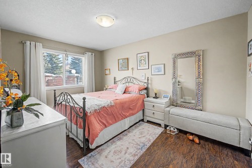 This room features wood flooring, a window with white curtains, and light-colored walls - 21 1850 Mill Woods Road E, Edmonton, AB - Indoor Photo Showing Bedroom