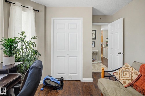 This versatile room features warm-toned flooring, light-colored walls, and a window with white curtains - 21 1850 Mill Woods Road E, Edmonton, AB - Indoor
