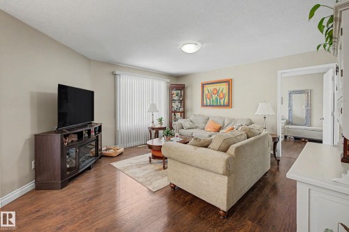 The living area features hardwood floors and neutral-toned walls, creating a welcoming atmosphere - 21 1850 Mill Woods Road E, Edmonton, AB - Indoor Photo Showing Living Room