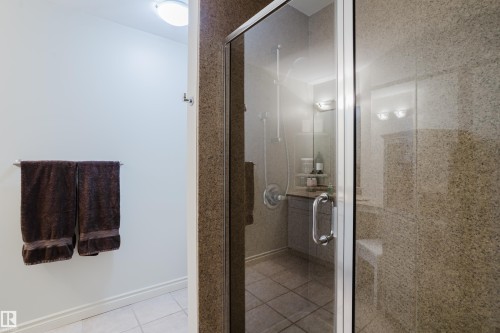 The bathroom features a glass-enclosed shower with stone-look tile walls and a tiled floor - 206 10108 125 Street, Edmonton, AB - Indoor Photo Showing Bathroom