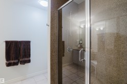 The bathroom features a glass-enclosed shower with stone-look tile walls and a tiled floor - 